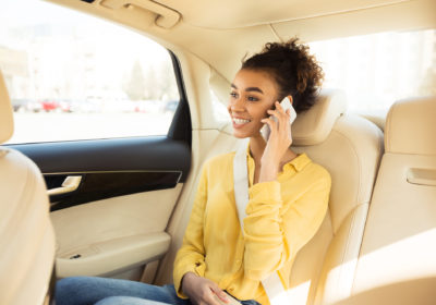Smiling Black Woman Talking On Phone Sitting In Taxi Cab